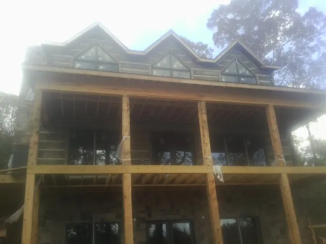 Dormers and porch framing on a large log home under construction — Roof Coating work by our crew in Hickory